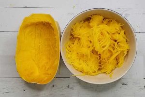 picture of hollowed out spaghetti squash and bowl full of cooked squash