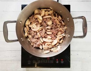 picture of beef and sliced mushrooms simmering in pot