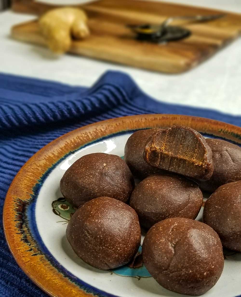 ginger molasses cookie dough bites on plate with cutting board in background