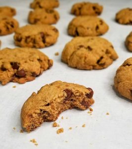 baked cookies with one half eaten cookie in front