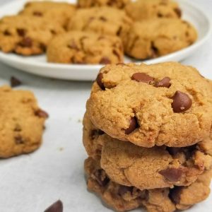 stack of baked cookies with plate of more cookies in background