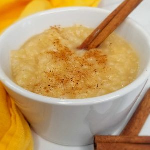 Bowl of eggnog rice pudding with cinnamon stick sticking out of the top