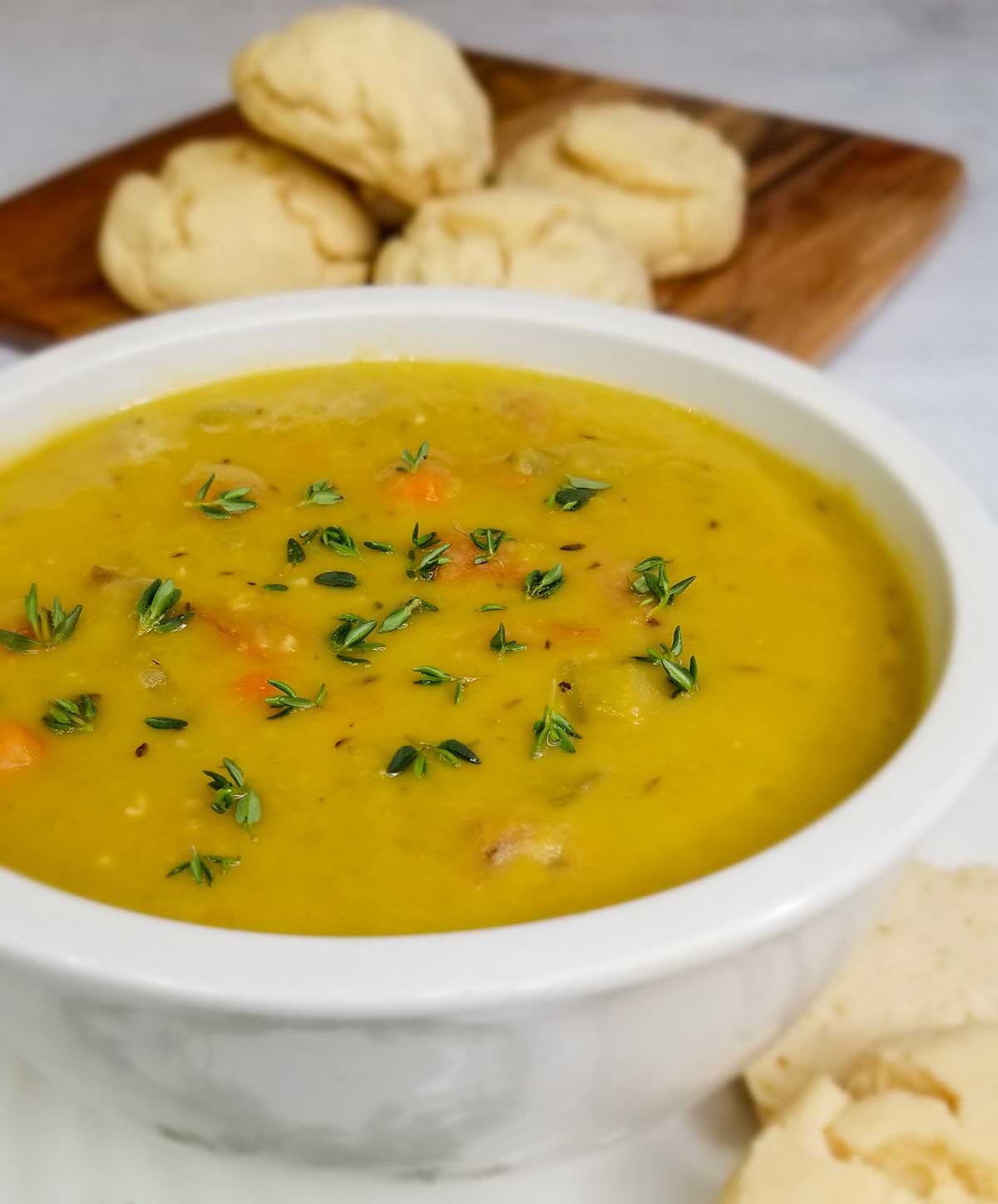 ham bone split pea soup in bowl with biscuits in background