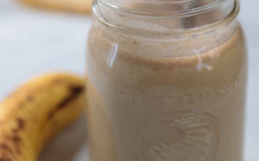Peanut butter banana oat smoothie in glass jar with banana