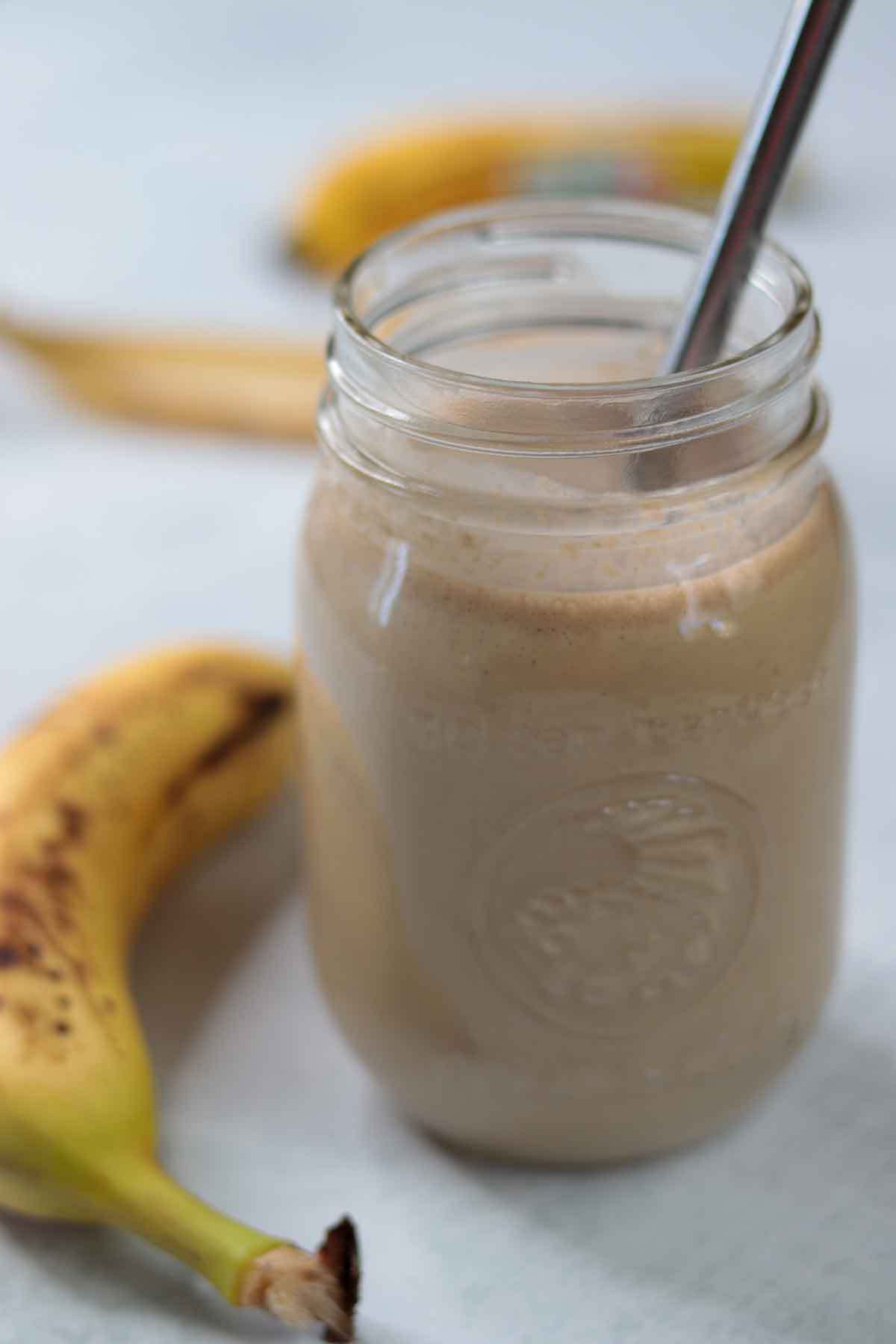 Peanut butter banana oat smoothie in glass jar with banana