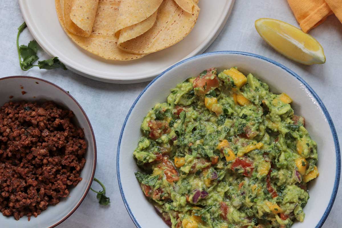 Mango avocado salsa surrounded by taco beef, corn tortilla shells and fresh lemon