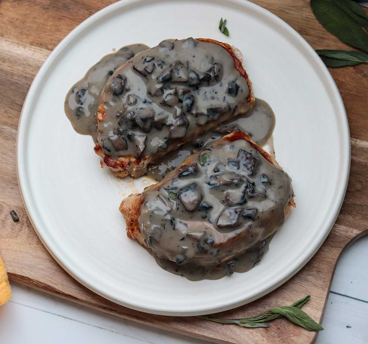 Top-down view of two pork chops covered in dairy free mushroom sauce