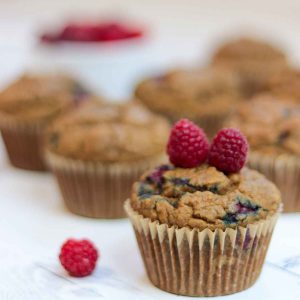 One raspberry muffin with two raspberries sitting on top of it