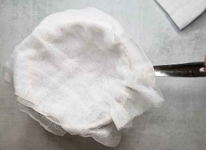 Cheesecloth on top of strainer and large glass measuring dish