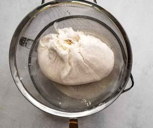 Sack of tiger nut pulp in cheesecloth over strainer