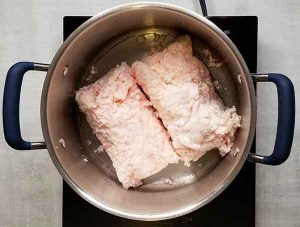 Beef suet fat trimmings sitting in a pot on a burner