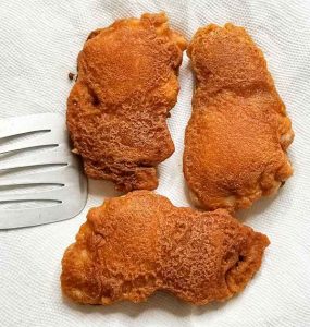 three pieces of fried chicken on paper towel beside spatula