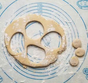 What your dough will look like after cutting out all of your doughnuts and before rerolling it and making more. Scraps of dough on floured surface.