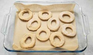 Cut out doughnuts on parchment paper in deep glass dish