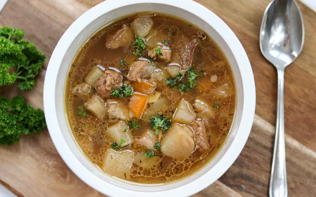 Bowl of stew on a cutting board with fresh parsley and a spoon