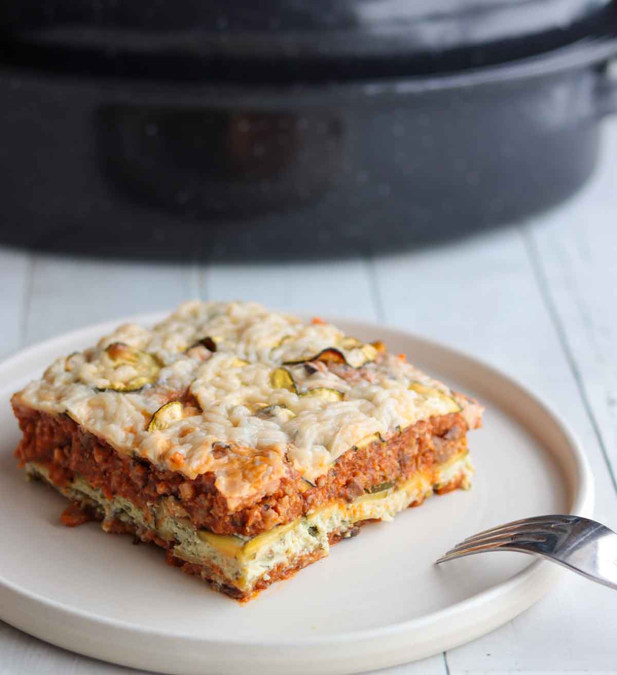 square serving of dairy free zucchini lasagna sitting on a white plate with fork on side