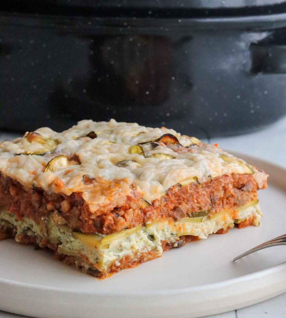 close up view of zucchini lasagna serving sitting on plate with fork