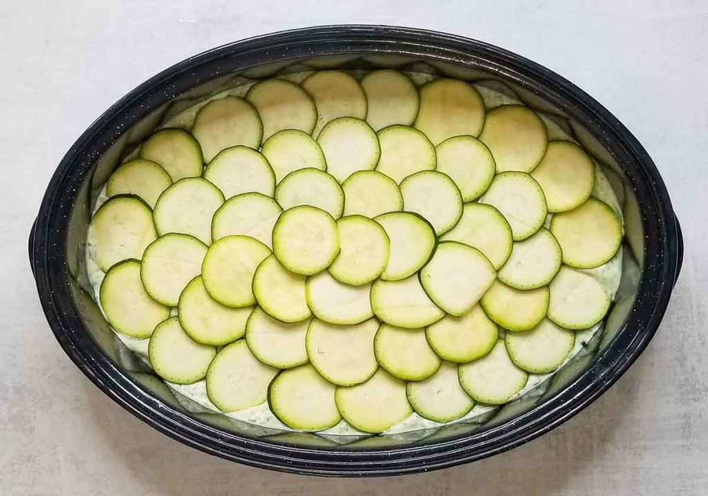 layer of zucchini medallions on top of cheese sauce and other layers