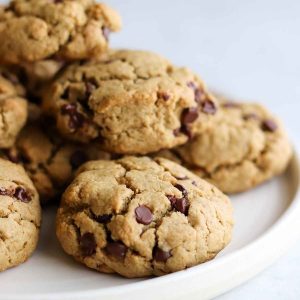 Chocolate chip cookies piled high on a white plate