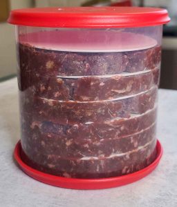 Ground meat with burger seasonings in burger press