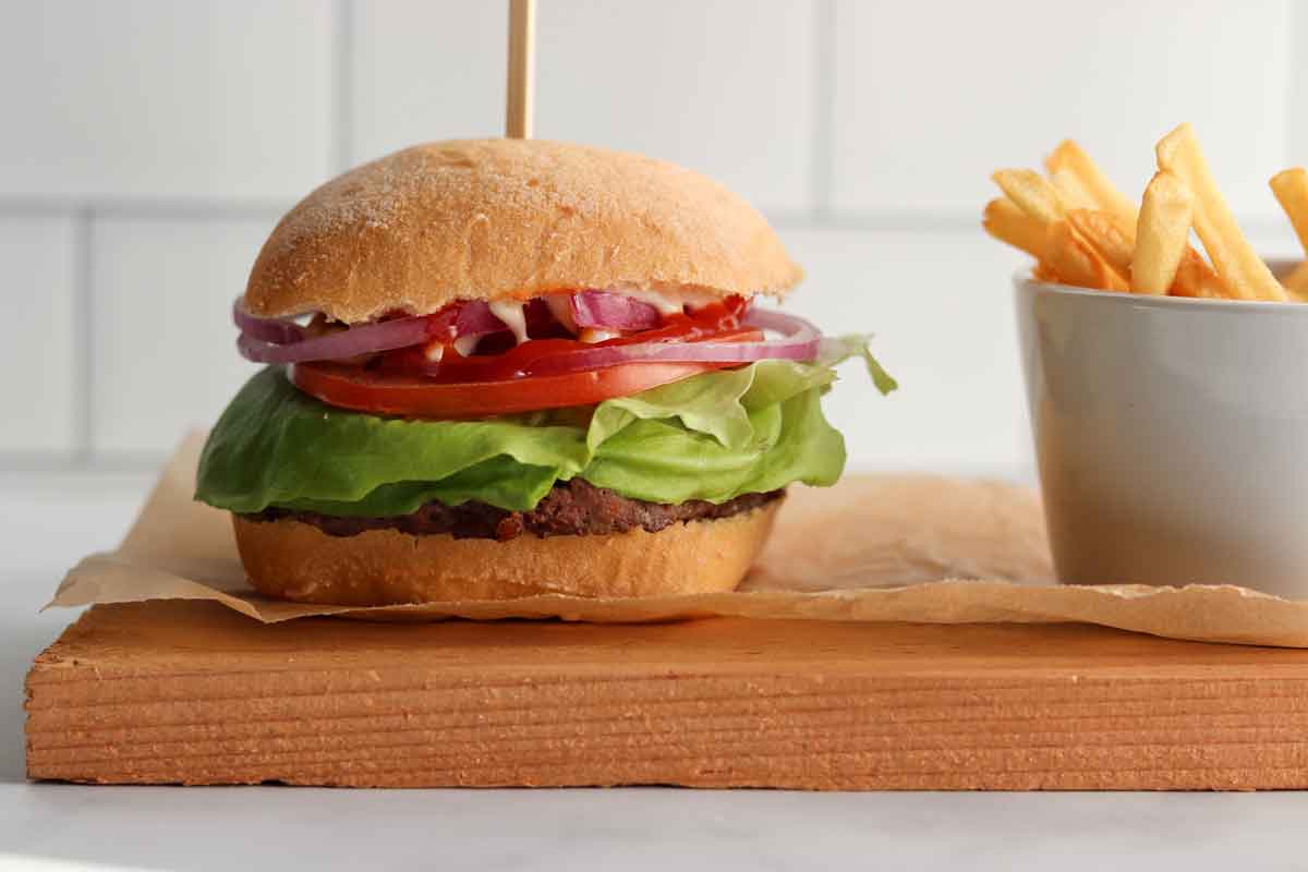 Side view of caribou burger on a bun with a side of fries