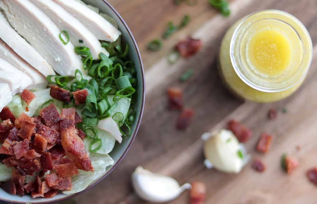 Dairy free caesar dressing overtop view sitting beside delicious looking ceaser salad