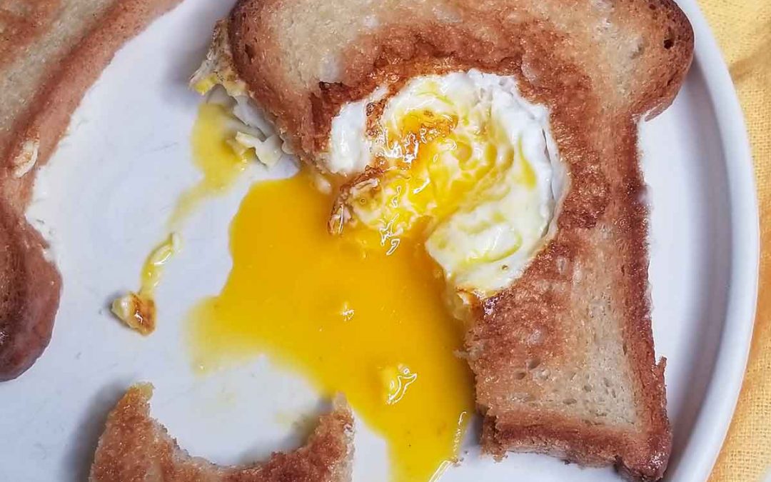 Scotch egg dripping out of toast on white plate