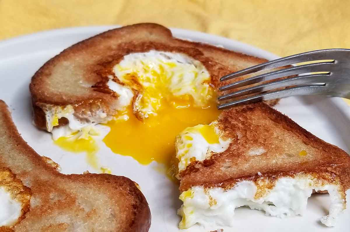 close up on egg dripping from toast on plate