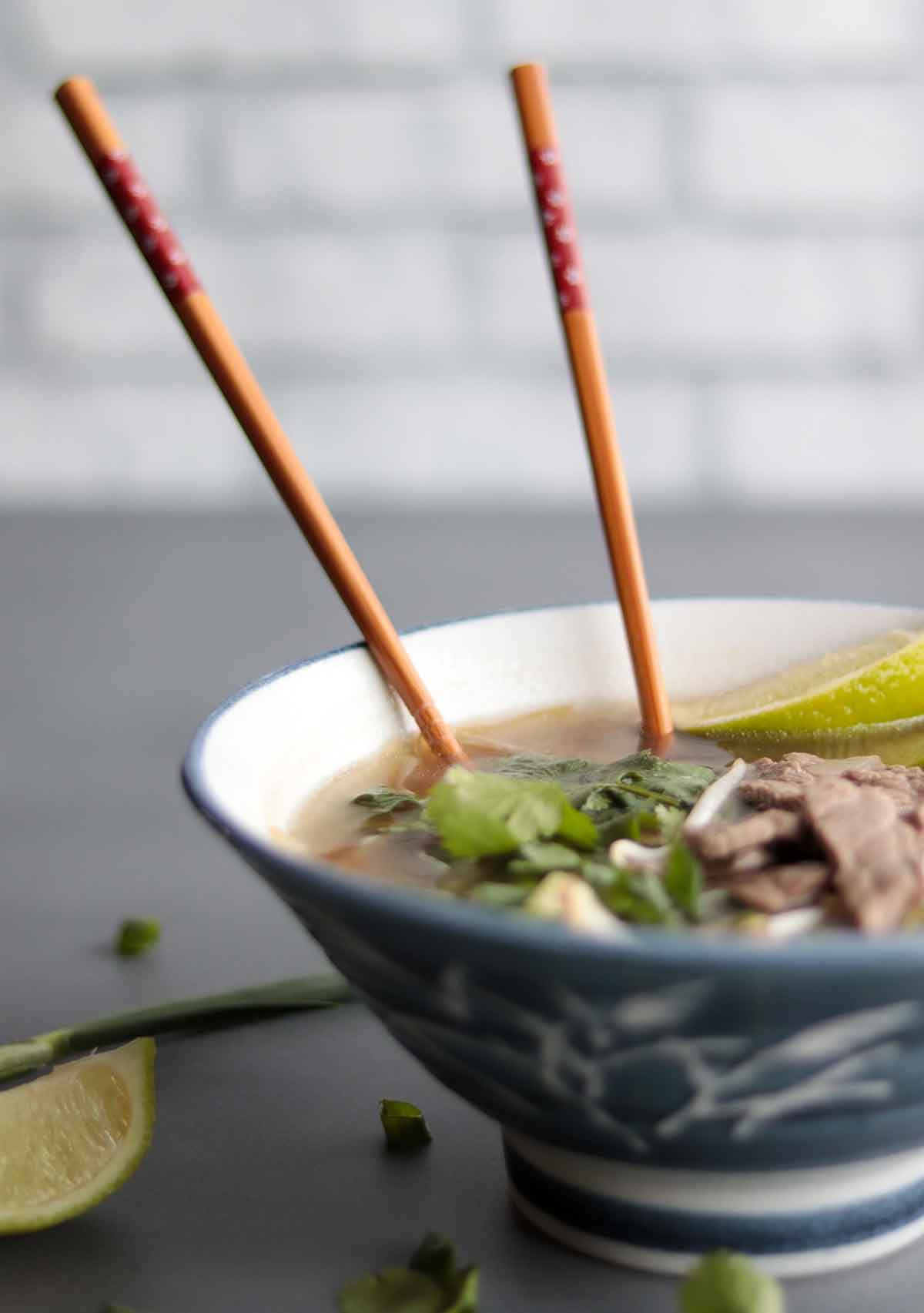 close view of keto pho in blue ceramic bowl with chopsticks plunged into bowl