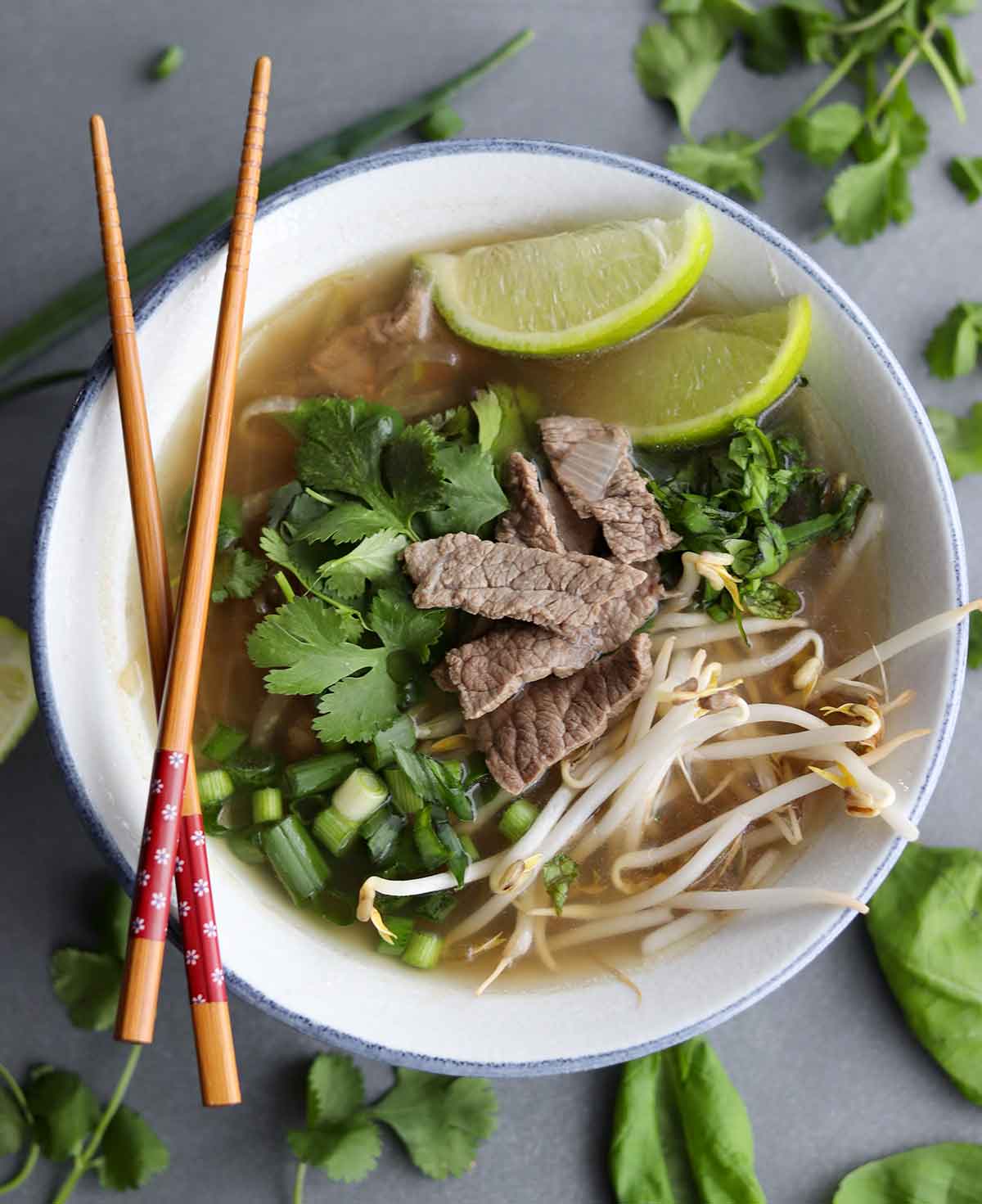 overhead view of keto pho with chop sticks resting on side of bowl, garnished with lime and cilantro