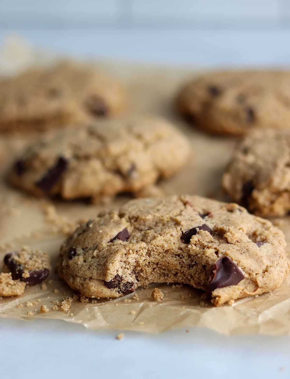 Chocolate chip cookies placed on parchment paper with a clean bite out of one cookie