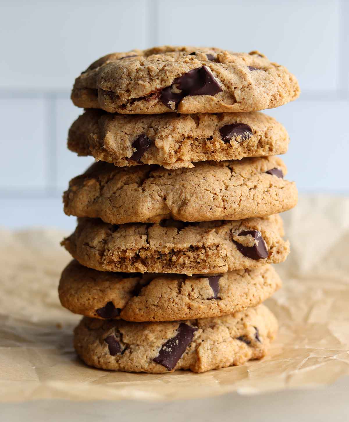 Tiger nut chocolate chip cookies stacked on top of each other and placed on top of parchment paper