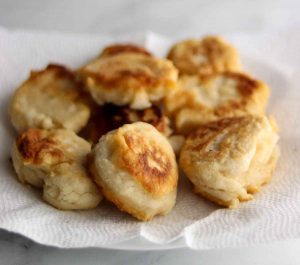 Full batch of golden brown gluten free bannock placed on a paper towel covered plate