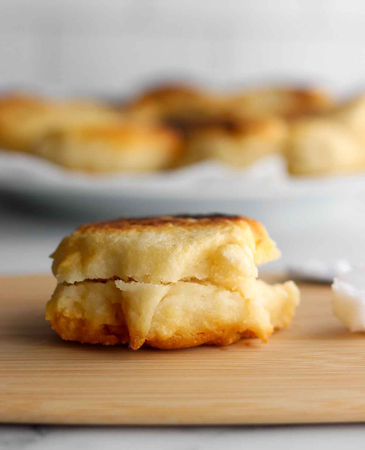 Close up view of golden brown gluten free bannock cut in half and placed on a wooden cutting board