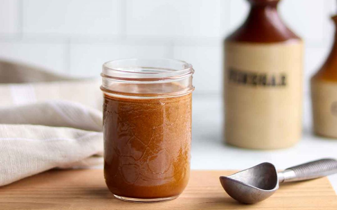 Gluten free worcestershire sauce sitting ontop of a wooden cutting board in a glass mason jar.