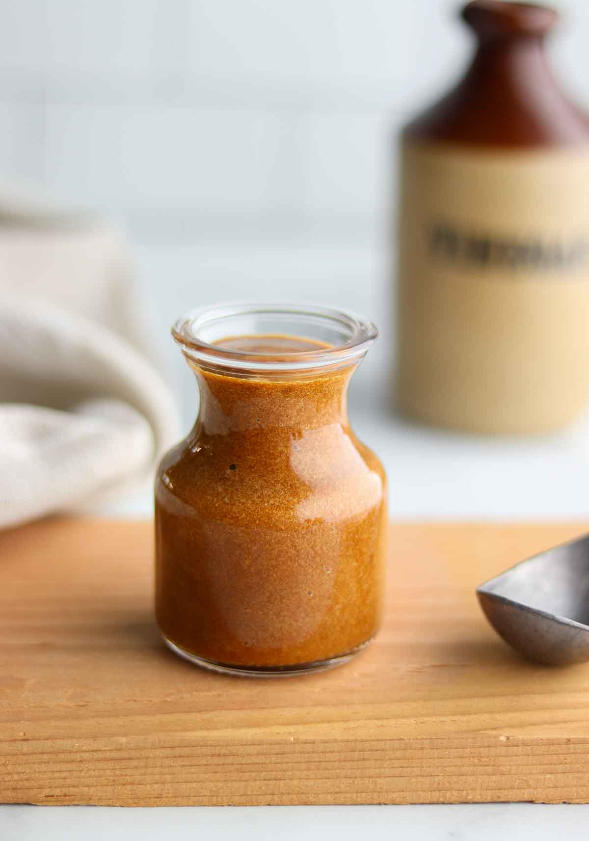 Close up view of gluten free worcestershire sauce in a small open mouth dressing jar with ingredients in back ground