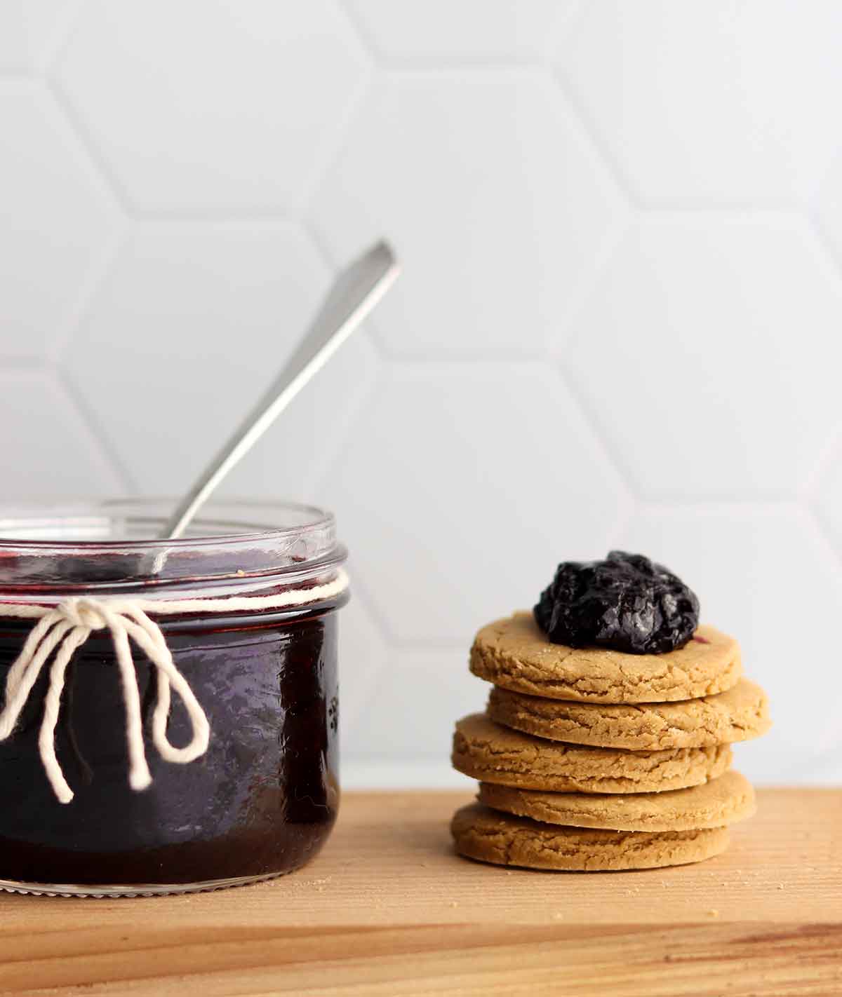 jar full of haskap jam with a stack of biscuits to the side with a dollop of jam placed on top