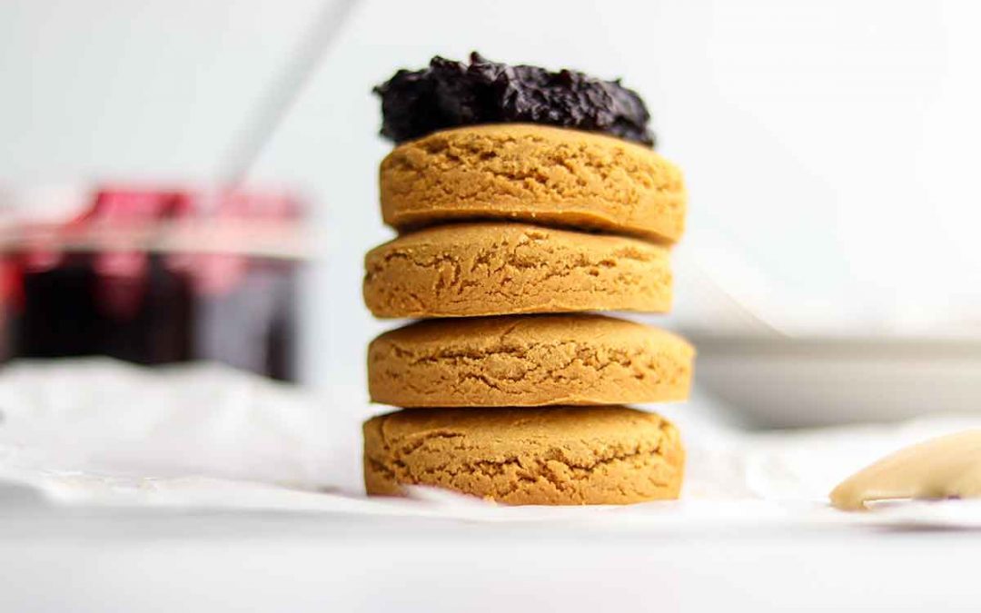 Close up view of stacked oat flour biscuits with a dollop of jam on top