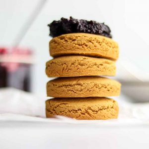 Close up view of stacked oat flour biscuits with a dollop of jam on top