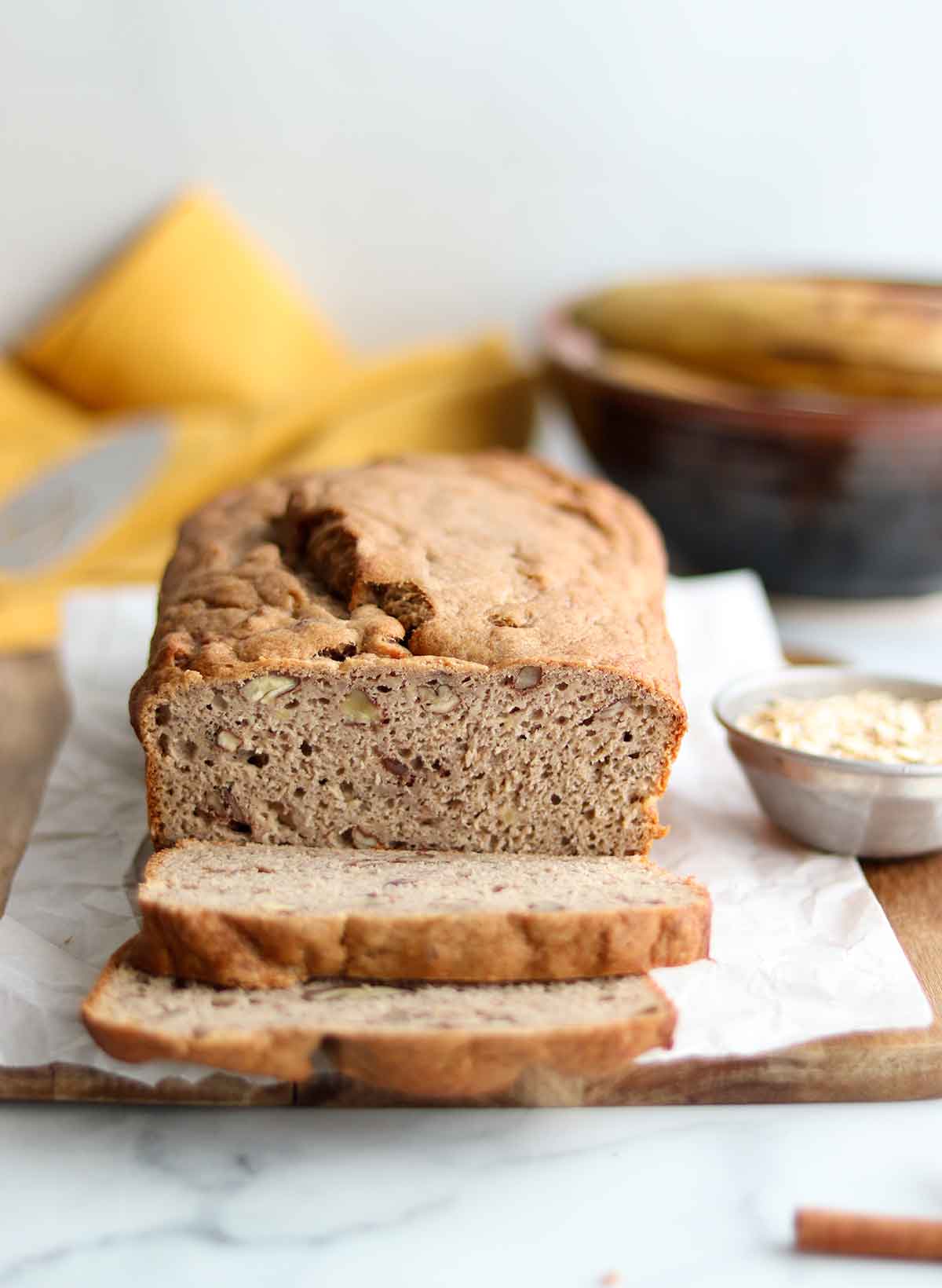 Sliced oat flour banana bread loaf surrounded by ingredients