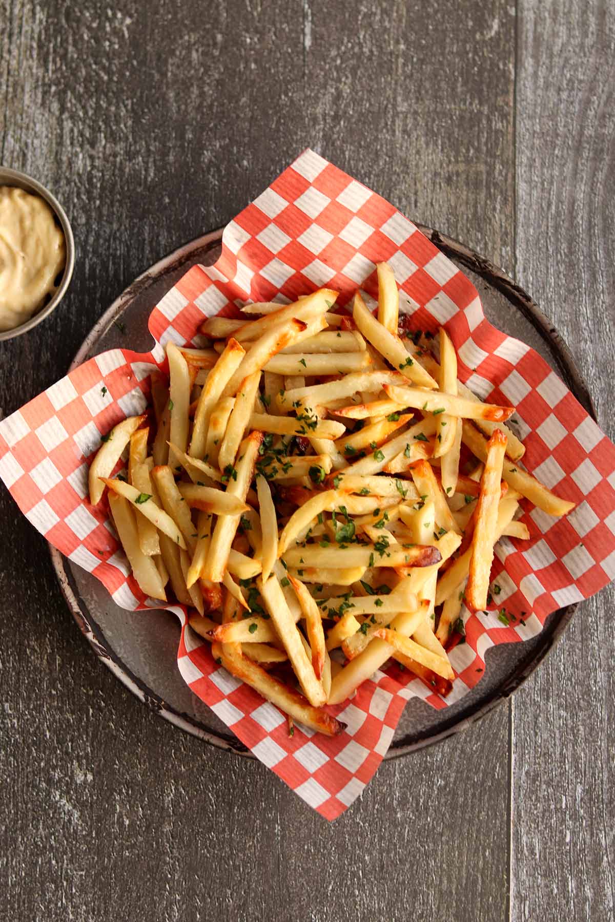 Overhead view of a full basket of truffle fries lined with white and red checkered parchment paper