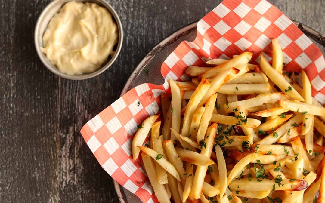 Close up overhead view of truffle fries served on classic checkered paper with a side of dip