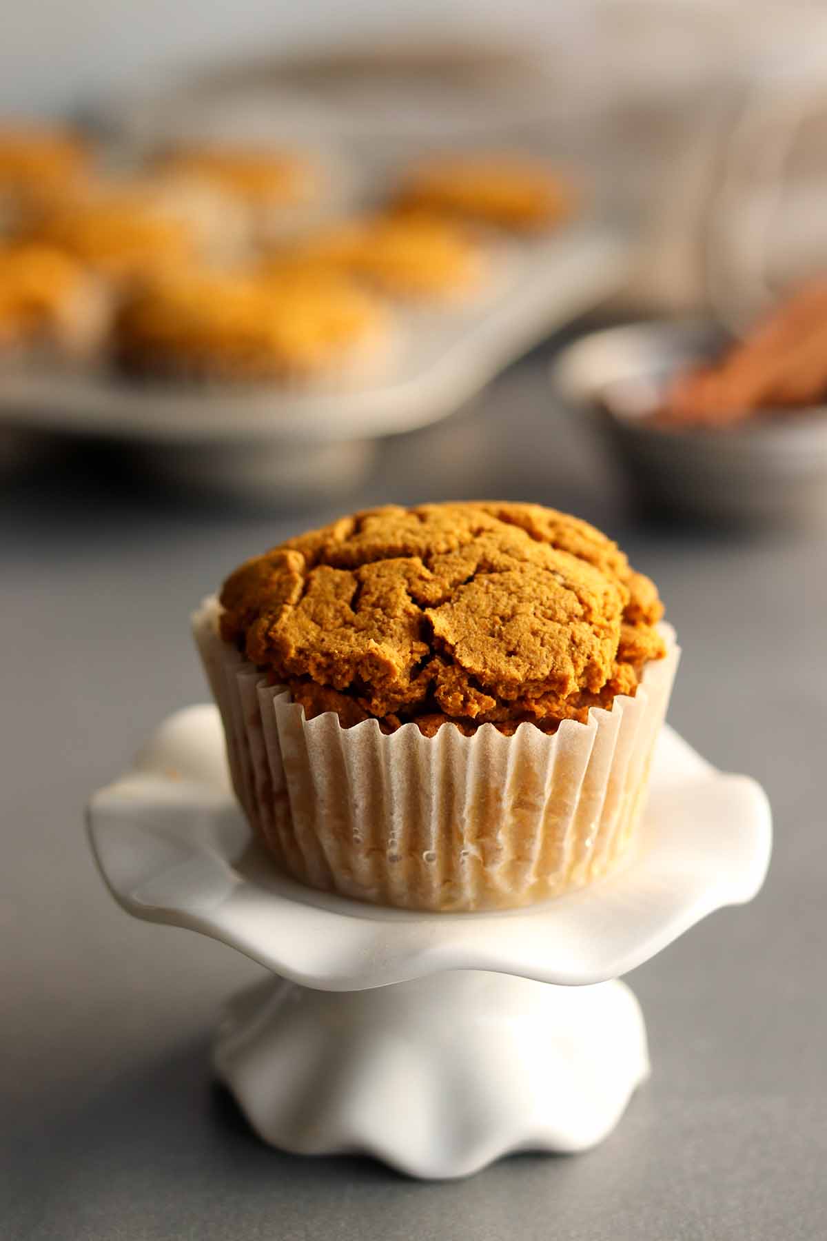 A pumpkin muffin placed on a decorative ceramic cup cake stand