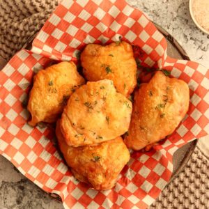 Overhead view of crispy chicken thighs served in white and red checkered parchment paper