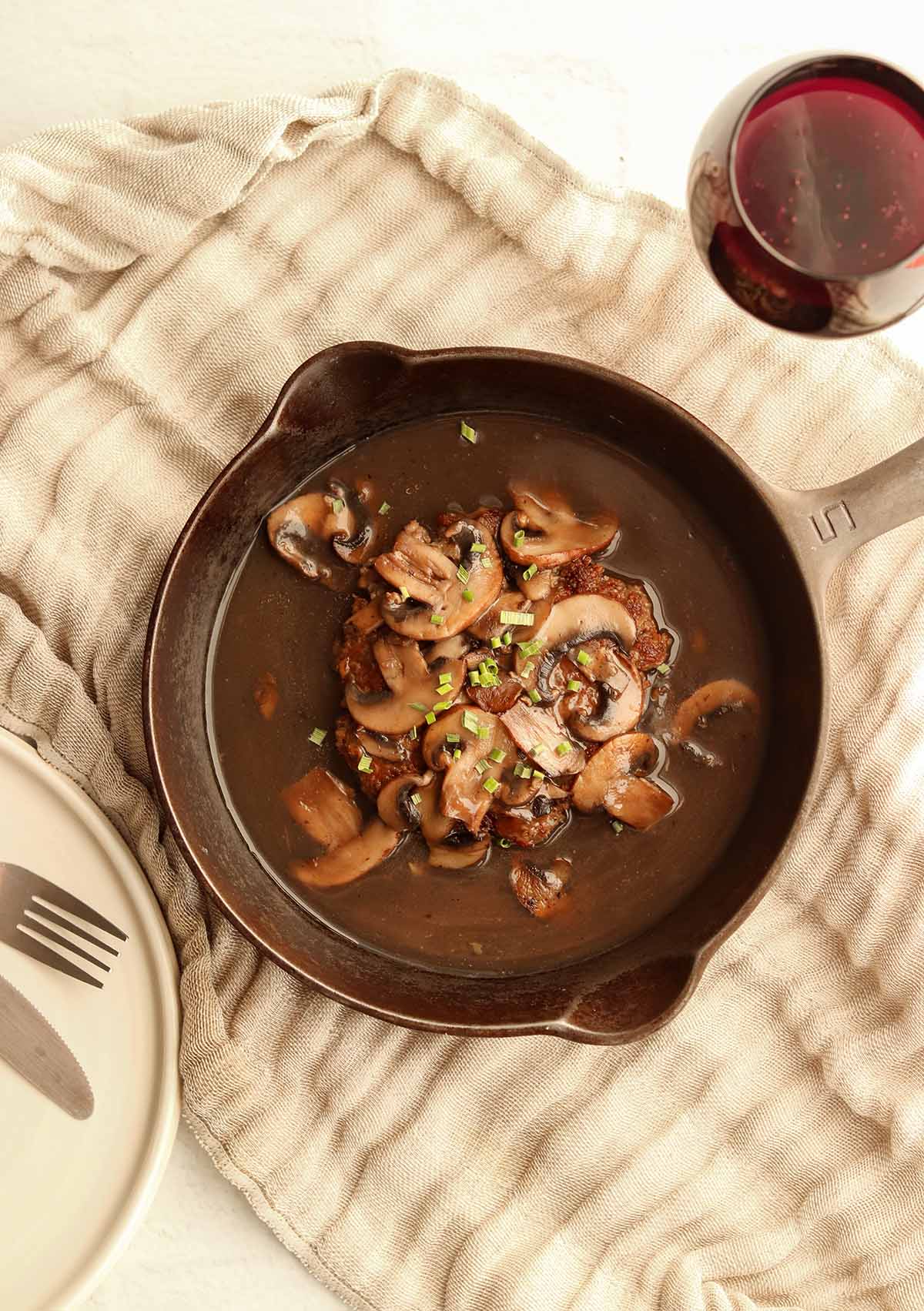 Zoomed out view of Salisbury steak in a skillet