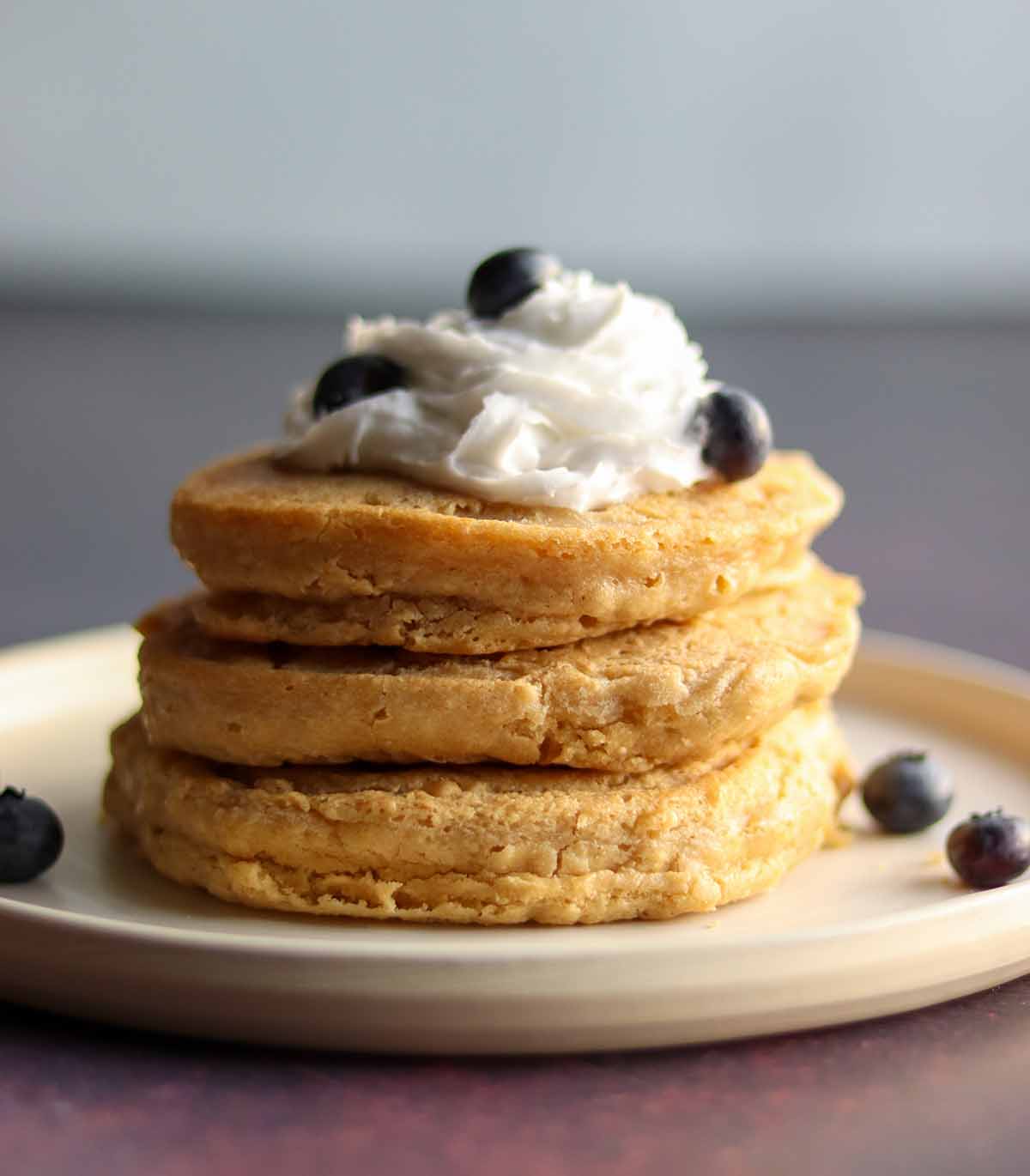 Close up side view of fluffy oat flour pancakes stacked high with toppings