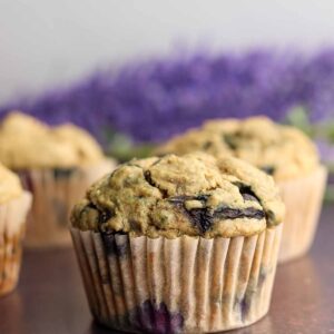 Golden brown blueberry oat muffins in front of a bouquet of lavender