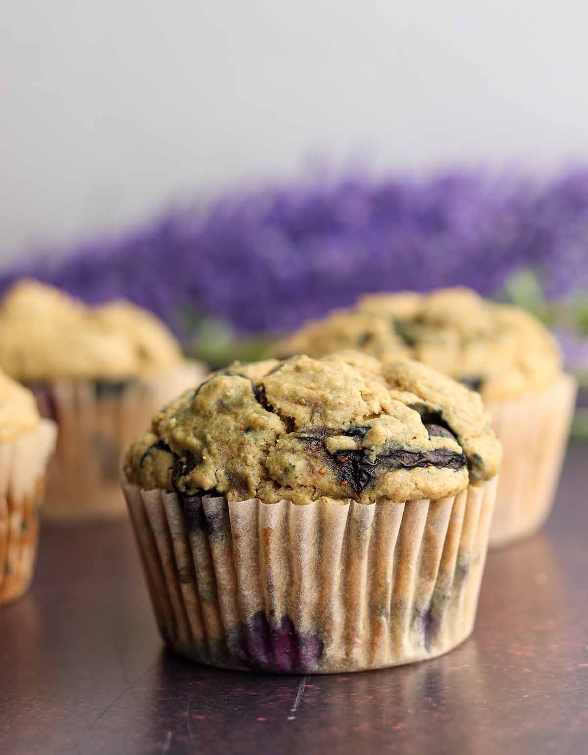 Golden brown blueberry oat muffins in front of a bouquet of lavender