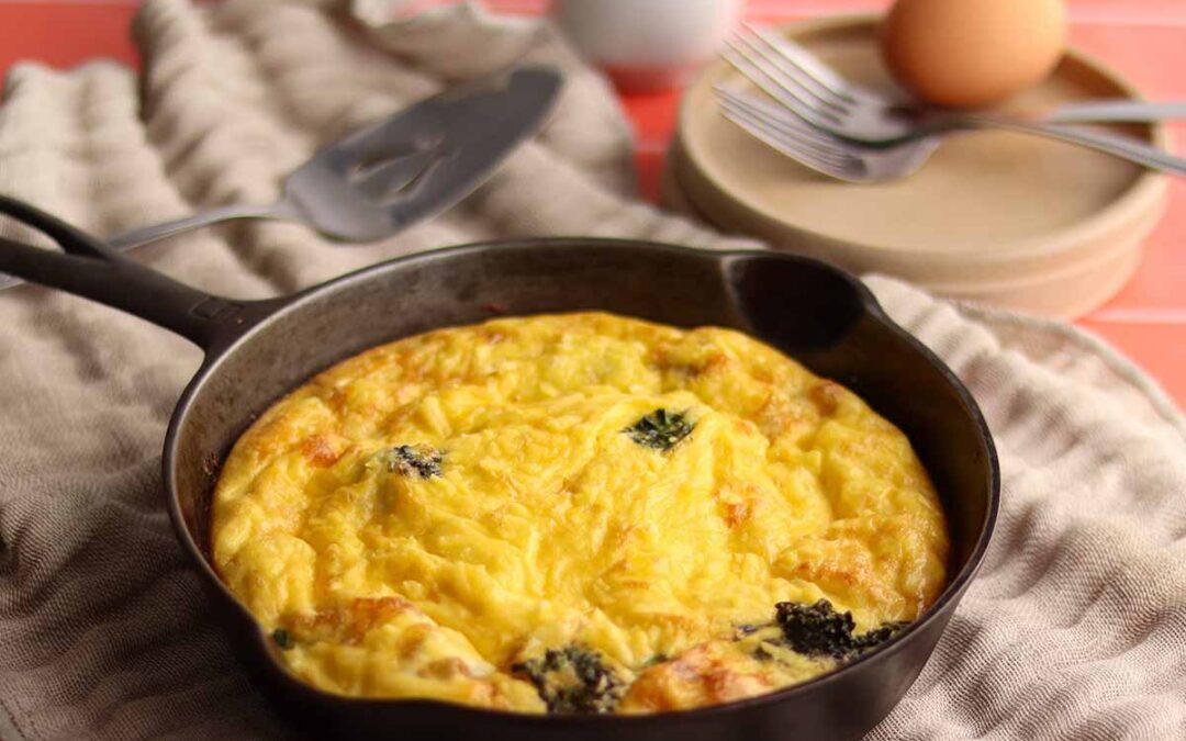 Overhead view of dairy free frittata in a cast iron pan surrounded by two cups of coffee and ingredients