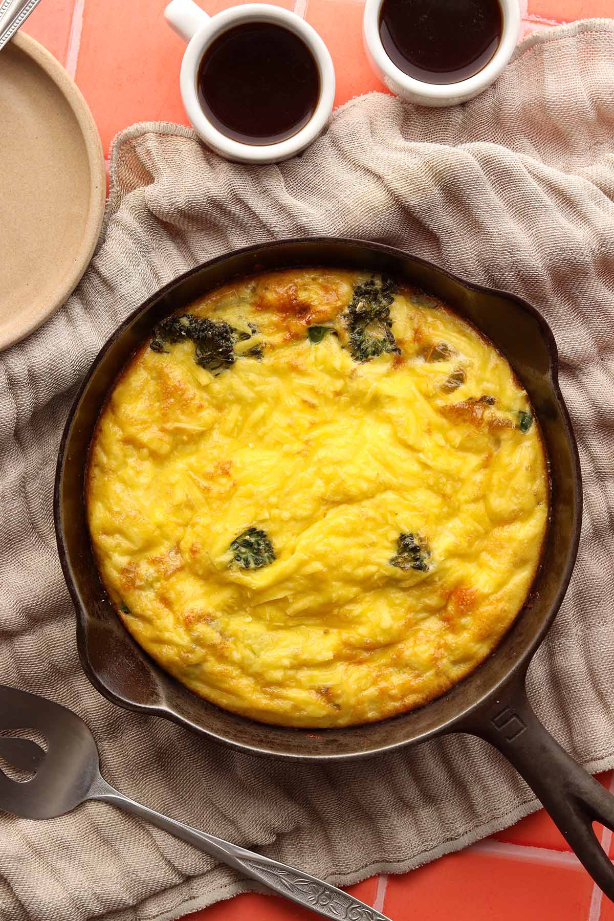 Close up view of dairy free frittata in a cast iron pan surrounded by ingredients 